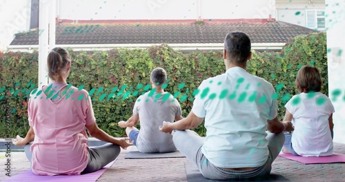 Fotografie Practicing four adults seated meditating on patio, with pink purple gray mats an