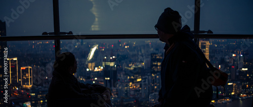 Quadro em tela Silhouettes of a couple looking at the illuminated city skyline from a high rise