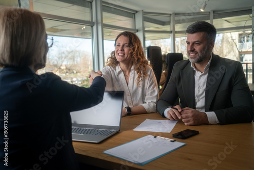 Obraz na plátně Smiling lawyer, realtor or financial advisor handshaking young couple thanking f