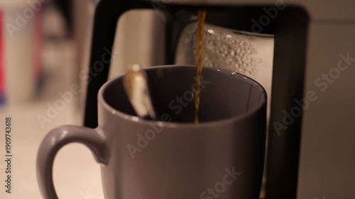Coffee maker pouring espresso in a cup