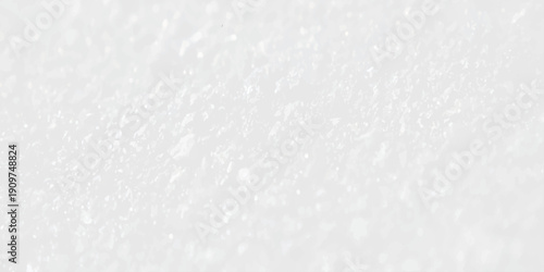 A closeup macro of white sugar crystals creates a textured frost pattern on a light surface, resembling a cold winter snow background with a natural marble stone design