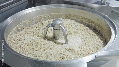 Industrial cabbage mixing in a stainless kettle for pie filling.