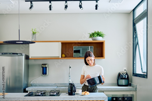 Canvastavla Woman preparing food in her bright home kitchen, placing pastries into an air fr
