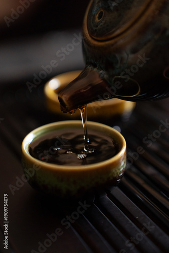 Pouring Tea from Teapot into Small Cup on Tea Table