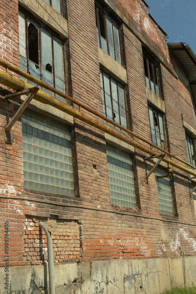 Obraz premium Industrial building with weathered walls and structural details. Worn textures, exposed materials, and industrial decay. Raw, atmospheric view of past urban infrastructure.