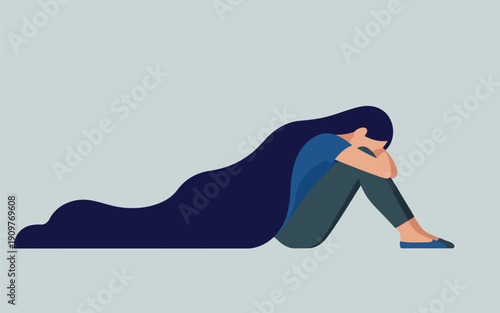 A solitary young woman with long dark hair sits sadly curled up on the floor facing left