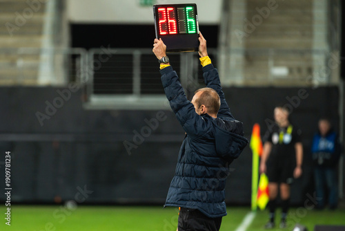 Fotografie Team manager man shows players substitution during football match