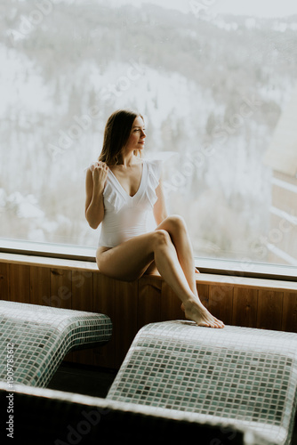 Woman sits by a large windo...