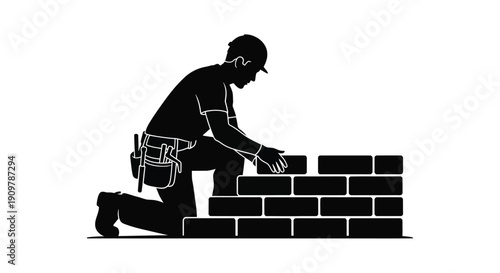 Silhouette of a construction worker kneeling and laying bricks