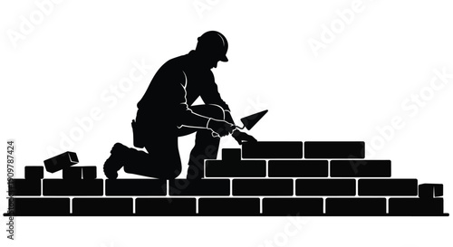 Silhouetted construction worker laying bricks on a partially built wall