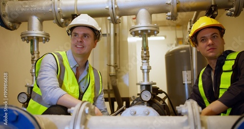 Принти на полотні Two engineers collaborate, intently inspecting complex industrial pipes and machinery in a bright plant room