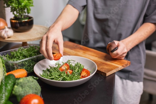 Photos teen boy preparing fresh vegetable salad in modern kitchen, healthy lifestyle an