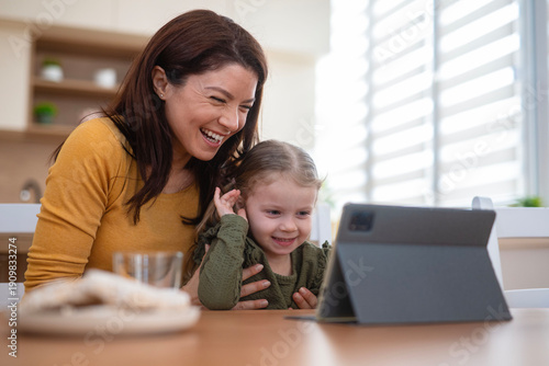 Mother and daughter laughing watching content on tablet