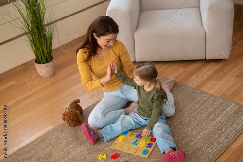 Mother and daughter high-fiving playing a numbers puzzle