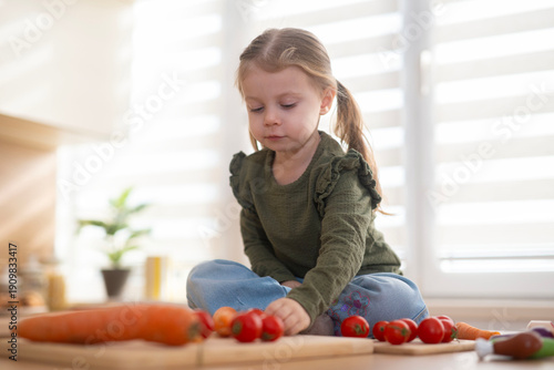 Little girl playing with fresh cherry tomatoes