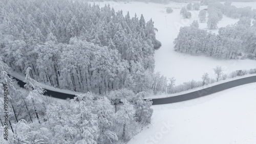 Landstraße durch verschneiten Wald Drohnenaufnahme
