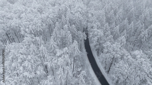 Landstraße durch verschneiten Wald Drohnenaufnahme