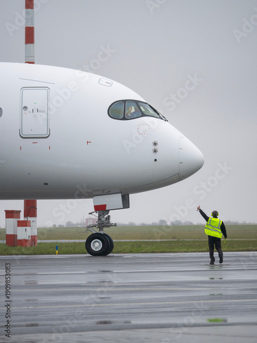 Airport ground crew worker giving thumbs up signal to airplane pilot before departure