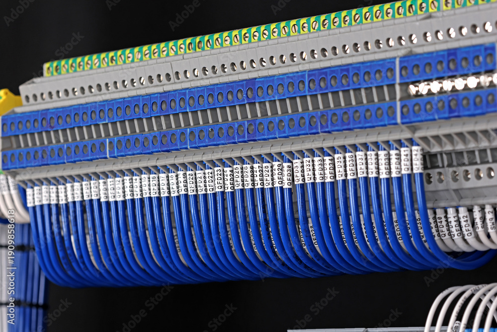 Fototapeta premium Electrical terminals with connected insulated wires with metal lugs. It is installed on a metal mounting rod in the electrical panel. 