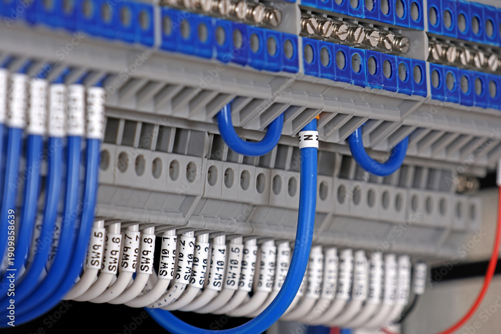 Fototapeta premium Electrical terminals with connected insulated wires with metal lugs. It is installed on a metal mounting rod in the electrical panel. 
