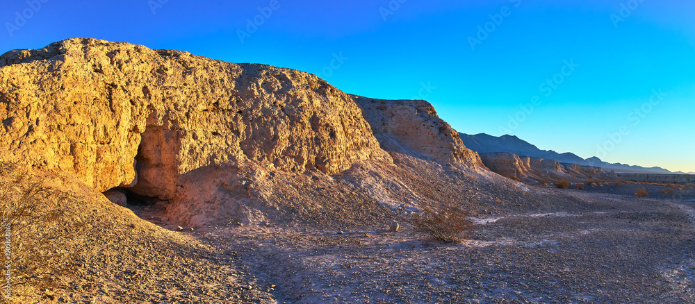 Obraz premium Panorama of Sunlit Fossil Bed Cliffs and Desert Plain at Golden Hour
