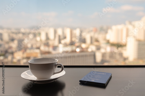 Coffee Cup and Passport on Table with Blurred City Skyline Background – Business Travel Concept
