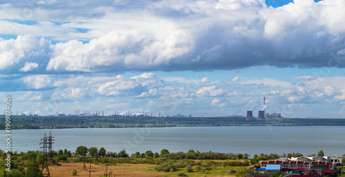 Power plant by lake under bright beautiful clouds