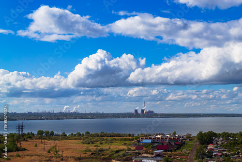 Power plant by lake under bright beautiful clouds