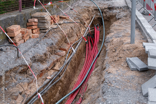 Excavation trench with red utility cables and bricks
