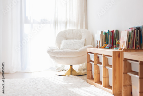 Fotografía Cozy Scandinavian kids room corner with soft armchair, wooden toy storage shelf and colorful children’s books