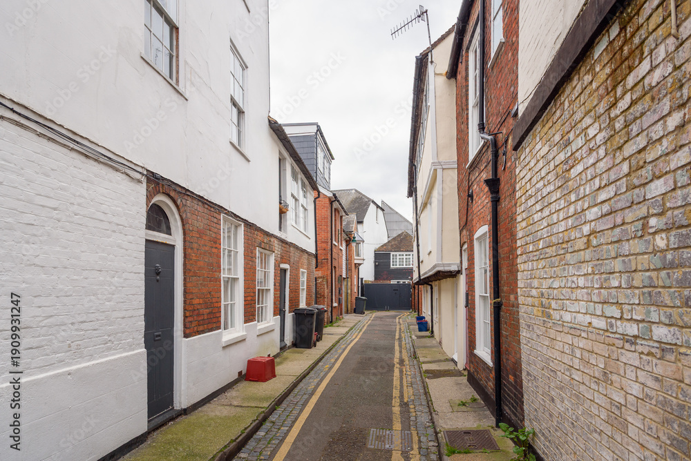 Fototapeta premium Deserted alley lined with old brick residential buildings on a cloudy spring day
