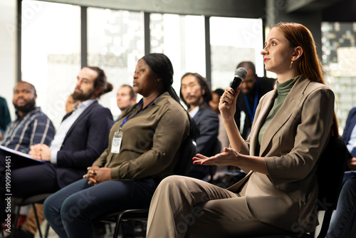 Photography Young adult businesswoman in audience interacting with presenter, asking questions and engaging in debate