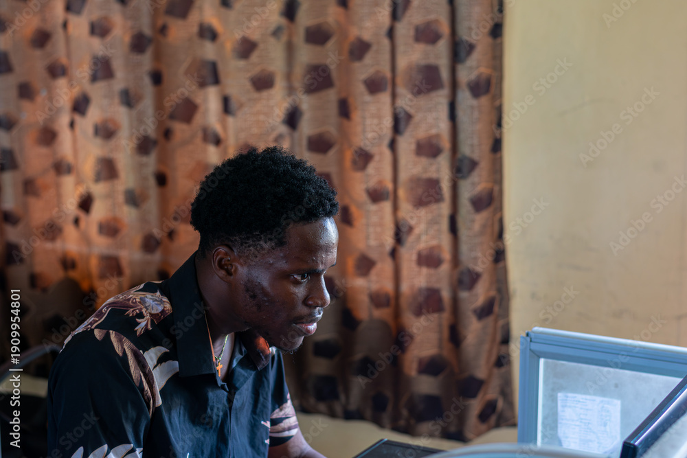 Fototapeta premium Young African student using a computer in school