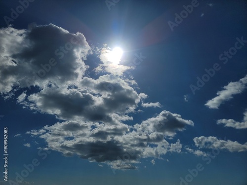 Schilderij op canvas Bright sun in the deep blue sky with cottony white clouds.