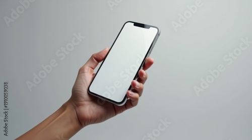 A person holding a smartphone with a blank screen against a plain background.
