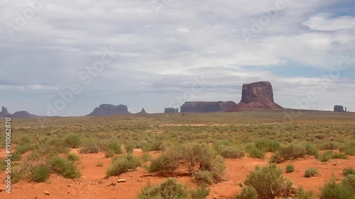 Panning shot of the American southwest scenery, featuring desert and red rock formations, on an overcast cloudy day.