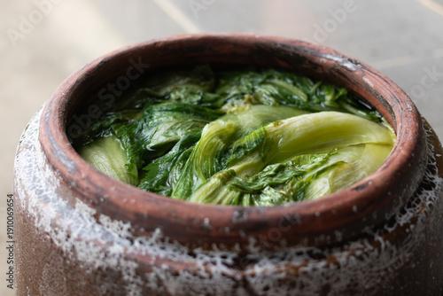 Traditional fermented mustard greens in a classic clay jar, a popular and flavorful fermented side dish in Vietnamese family meals