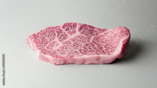 A large, marbled piece of Wagyu beef is displayed on a white surface, showcasing its intricate muscle structure and vibrant pink color.