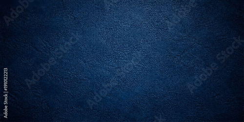 A dark blue grunge denim fabric texture with a rough cotton canvas pattern creates a deep navy textile surface design for a weathered clothing material backdrop