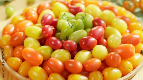 Colorful premium cherry tomatoes in red, yellow, orange and green tones filling the frame, fresh organic produce concept for healthy eating, vegan diet and farm to table food on wooden table.
