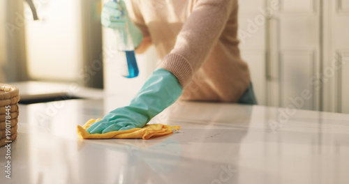 Fotografia Person, hands and cleaning surface with detergent in kitchen for housekeeping or hygiene in home