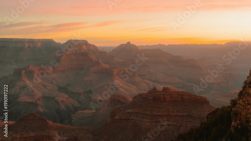 Vast canyon landscape featuring layered rock formations under a soft pastel sunset sky