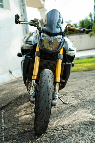 Moto roadster noire sportive avec fourche dorée – vue avant et détails en extérieur