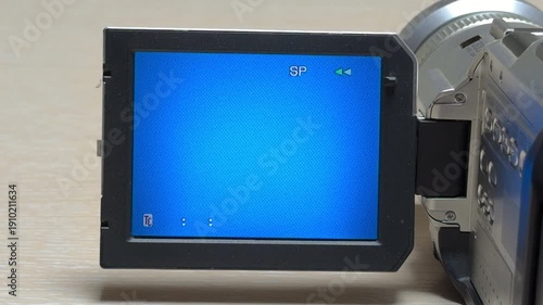 A nostalgic camcorder rewinds a tape against a blue display. The internal motor produces a mechanical whir and high-pitched whine as the spools spin quickly.