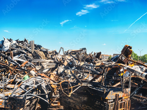 Fotografie A massive pile of crushed metal scraps lies under a clear, sunny sky