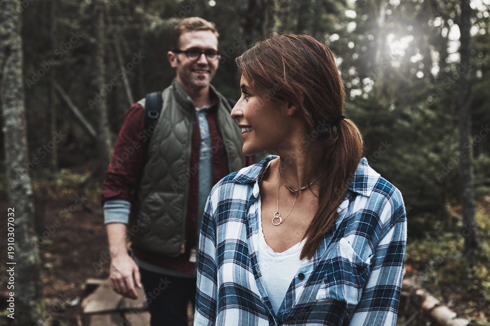 Fototapeta premium Smile, couple and hiking for travel in forest for adventure, trekking trip or bonding on holiday. Happy, people and walking in woods to explore nature, backpacking and daydreaming on vacation outdoor