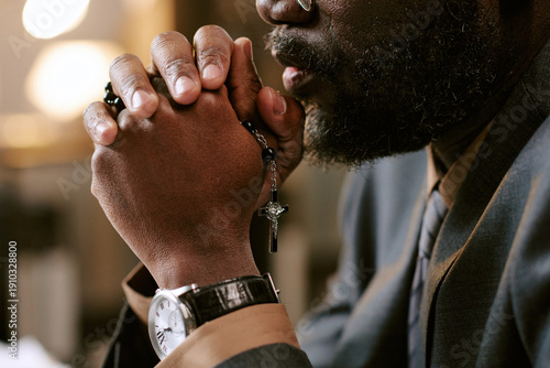 Canvastavla Black man clasping hands in thoughtful gesture while holding rosary with cross,