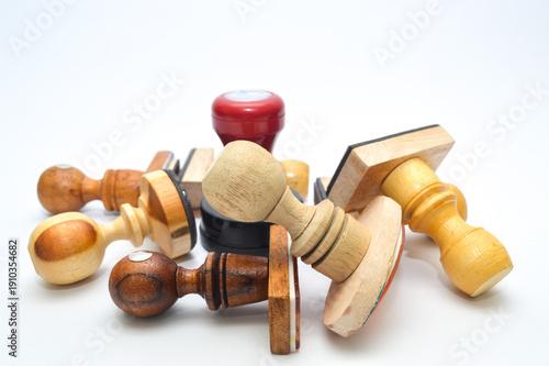 A pile of various vintage wooden rubber stamps isolated on a white background. Classic office stationery and business tools for documentation, approval, and legal branding.