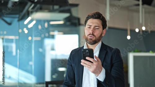 Professional man in office receives disappointing news on phone. Feelings of stress, frustration, and worry clearly visible. Dealing with problem or challenge.