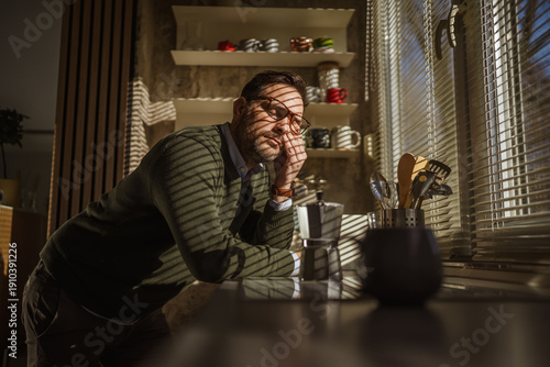 Fotografija Sleeping man leaning on kitchen counter needing coffee